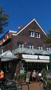 ein Backsteingebäude mit Leuten, die an Tischen davor sitzen in der Unterkunft Hotel Nordwind in Langeoog