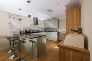 a kitchen with white cabinets and a island with bar stools at Luxurious home overlooking Cruden Bay golf course in Cruden Bay