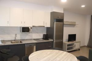 a kitchen with white cabinets and a table with a sink at APARTAMENTOS AGUAMARINA in Peñíscola