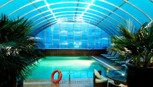 a swimming pool in a building with a blue ceiling at Al Safa Royal Suites in Doha