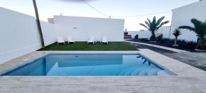 Una piscina al lado de un edificio blanco con sillas. en La Bonanza, en Timijiraque