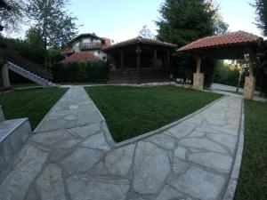 un patio trasero con una pasarela de piedra y un cenador en Vila Jovanka Zlatibor en Palisat