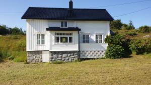 a white house with a black roof on a hill at Gammelstua in Hitra