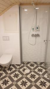 a bathroom with a shower with a toilet and a tiled floor at Gammelstua in Hitra
