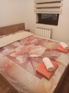 Una cama con dos toallas y una flor. en Apartman Casa Lukavica Istočno Sarajevo, en Lukavica