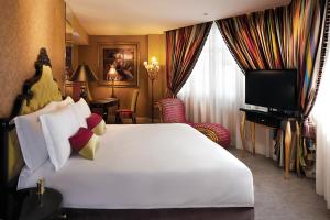a hotel room with a large white bed and a television at Aurum Royal in Singapore