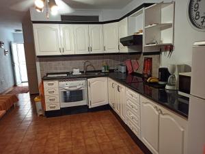 une cuisine avec des armoires blanches et des comptoirs noirs dans l'établissement Mare Verde - JOY, à Adeje