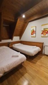 Duas camas num quarto com piso em madeira em Tredós, Casa adosada. Baqueira em Tredós