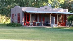 une petite maison avec une table et des chaises dans une cour dans l'établissement La Pausa Lodge de Campo, à Duggan