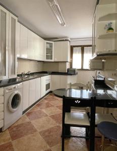 uma cozinha com armários brancos, uma mesa e uma máquina de lavar louça em CÓMODO alojamiento en Alba de Tormes em Alba de Tormes