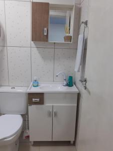 y baño con lavabo blanco y aseo. en Suíte Santin: o seu conforto está aqui!, en Foz do Iguaçu