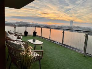 een balkon met stoelen en een tafel en uitzicht op het water bij Downtown Penthouse Budapest in Boedapest