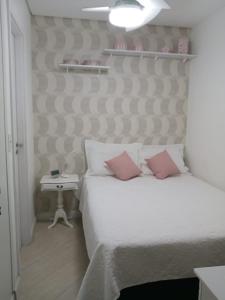 a bedroom with a white bed with pink pillows at Santos Unlimited 2 Dormitórios, 32o andar com vista Mar! in Santos