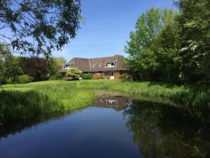 a house with a pond in front of it at Tetenshof für Pferdeliebhaber in Westerhever