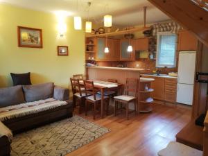 ein Wohnzimmer mit einem Sofa und einem Tisch sowie eine Küche in der Unterkunft Dulakówka - domek na każdą pogodę in Piwniczna-Zdrój