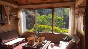 ein Wohnzimmer mit einem Tisch und einem großen Fenster in der Unterkunft Granja Los Conejos in Ramiriquí