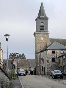 an old stone church with a clock tower on a street at Forest Lodge in Petit Mesnil