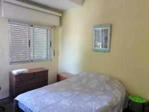 Un dormitorio con una cama y una cómoda y una ventana. en Casa del Mar, en Montevideo