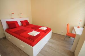 1 dormitorio con 1 cama con sábanas rojas y silla en Asha, en Cracovia