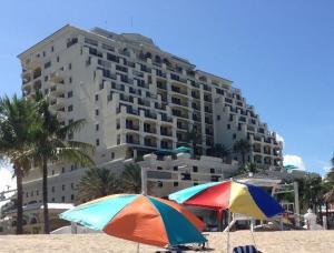 two umbrellas on the beach in front of a large building at The Atlantic Hotel & Spa Condo in Fort Lauderdale