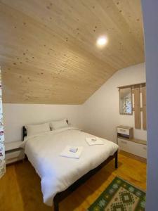 1 dormitorio con 1 cama blanca grande y techo de madera en Casa Arabela, en Vişeu de Sus