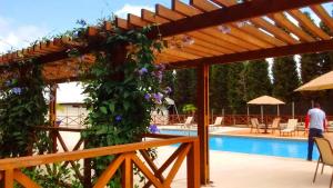 a pergola over a swimming pool with purple flowers at SUÍTE NO VISTA AZUL Vista para a Pedra in Pedra Azul
