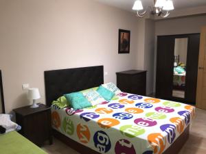 1 dormitorio con 1 cama grande y edredón colorido en Lacasadeyolandayedu en Medina del Campo