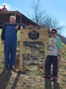 a man and a woman standing next to a sign at Mountain Memories Cabin Rental in Booneville