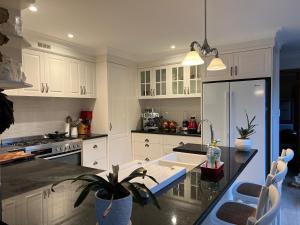 uma cozinha com armários brancos e um balcão preto em Luxury 4 bedroom house em Deewhy