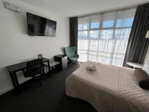 a hotel room with a bed and a desk and a television at Apartahotel Altos de la Sabana in San José