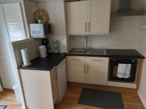 a small kitchen with white cabinets and a black counter top at 24 New Esplanade Court in Paignton
