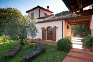 una casa con due panchine nel cortile di Agriturismo Podere Santa Rita a Montescudaio