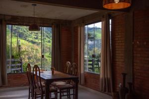 uma sala de jantar com mesa e cadeiras e uma grande janela em Oca Roça em Delfim Moreira