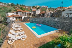 uma villa com uma piscina e espreguiçadeiras em Vila Maria Quinta 13 na Calheta