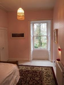 a bedroom with a window and a bed and a chandelier at Swinton Manse & Gardens in Swinton