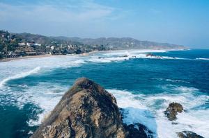 a beach with a large rock in the ocean at Hotel Boutique Madre Tierra in Mazunte