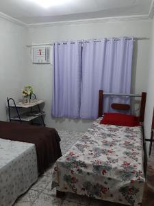 1 Schlafzimmer mit 2 Betten und lila Vorhängen in der Unterkunft Apartamento 1 Boa Vista 1 Caruaru in Caruaru