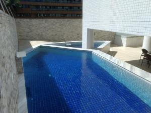 una piscina con azulejos azules en un edificio en Flat Famliar Beira-Mar 2 Camas de Casal AR Wi-Fi GAR Coz Lavadora, en João Pessoa