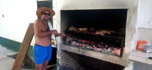 un hombre con un sombrero de pie junto a una chimenea en Chacra mita í, en La Cruz