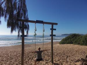 a woman sitting on a swing on the beach at Recanto Dos Vargas in Florianópolis