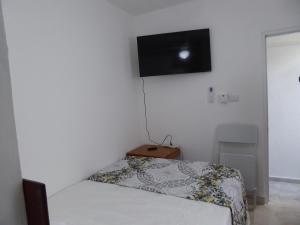 een slaapkamer met een bed en een flatscreen-tv aan de muur bij Cozy Studios-Private Entrance- HS Internet-AC-Hot Water-Backup Generator-near the Beach in San Felipe de Puerto Plata