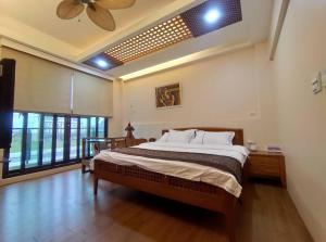 a bedroom with a large bed and a ceiling fan at Ciao Home in Toucheng