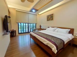 a bedroom with a large bed and a flat screen tv at Ciao Home in Toucheng