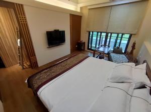 1 dormitorio con 1 cama blanca grande y TV en Ciao Home en Toucheng