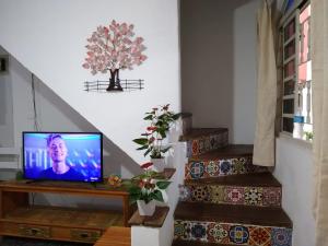 un televisor sentado en una mesa en una habitación con escaleras en Chalé da Ana - Ilhabela, en Ilhabela