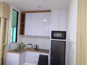 a kitchen with white cabinets and a black microwave at Era Amazing Manhattan Suite in Penampang