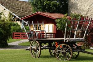 Un carruaje tirado por caballos con una casa pequeña. en Gites de La Croisée des Chemins - Piscine Chauffée - Spa, Hammam et Sauna, en Izeaux