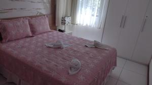 a bedroom with a pink bed with two hats on it at ILOA RESIDENCe in Barra de São Miguel +35 photos