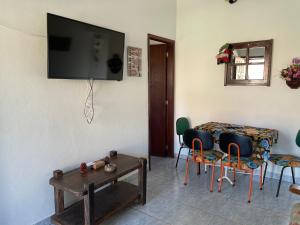 a living room with a table and a tv on the wall at Casa aconchegante - Búzios in Búzios