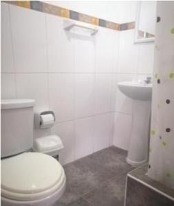 a white bathroom with a toilet and a sink at Hotel Kallma in Ica